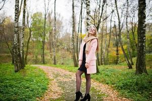 giovane ragazza bionda al cappotto rosa posato sul parco autunnale. foto