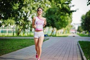 abbigliamento sportivo da ragazza su pantaloncini bianchi e camicia che corre al parco. foto