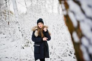 bella ragazza bruna in abiti caldi invernali. modello su giacca invernale e cappello nero. foto