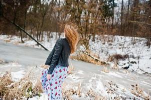 ragazza alla moda in giacca di pelle al giorno d'inverno contro il lago ghiacciato. foto