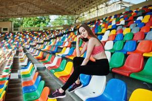 fitness ragazza sportiva in abbigliamento sportivo seduto allo stadio sedie sport all'aria aperta. donna sexy felice. foto
