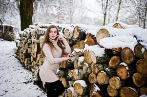 bella ragazza bruna in abiti caldi invernali. modello su maglione invernale vicino al moncone. foto