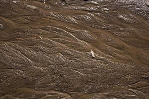 texture sabbia con linee ondulate e getti d'acqua in colori caldi. superficie sabbiosa dopo la pioggia foto