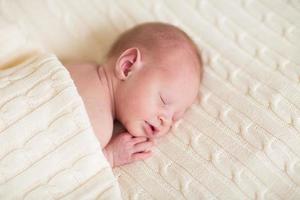 piccolo neonato che dorme su una coperta a maglia morbida foto