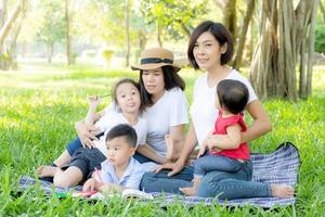 bella giovane famiglia di genitori asiatici picnic ritratto nel parco, bambino o bambini e madre amano felici e allegri insieme in estate al giardino, concetto di stile di vita. foto