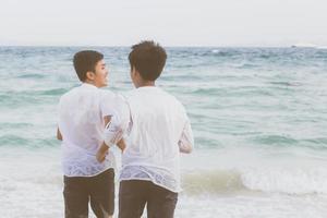 giovane coppia asiatica omosessuale che corre con allegro insieme sulla spiaggia in estate, turismo gay in asia per il tempo libero e relax con felicità in vacanza al mare, concetto legale lgbt. foto