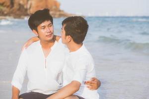 ritratto omosessuale giovane coppia asiatica seduta abbraccio insieme sulla spiaggia in estate, asia turismo gay per il tempo libero e relax con romanticismo e felicità in vacanza al mare, concetto legale lgbt. foto