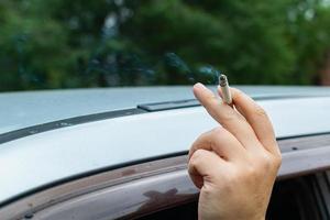 l'uomo ha allungato la mano con una sigaretta dall'auto foto