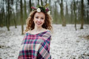 ragazza bionda riccia carina con corona in plaid a scacchi nella foresta innevata nella giornata invernale. foto