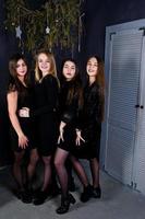 quattro ragazze carine amiche indossano abiti neri contro le decorazioni natalizie. foto