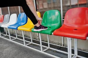 fitness ragazza sportiva in abbigliamento sportivo allo stadio di sport all'aria aperta. felice donna sexy lacci in maglia su scarpe da ginnastica. foto