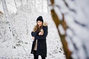 bella ragazza bruna in abiti caldi invernali. modello su giacca invernale e cappello nero. foto