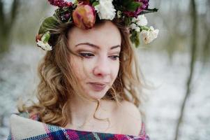 ragazza bionda riccia carina con corona in plaid a scacchi nella foresta innevata nella giornata invernale. foto