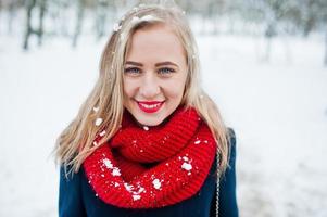 ritratto di ragazza bionda in sciarpa rossa e cappotto il giorno d'inverno. foto