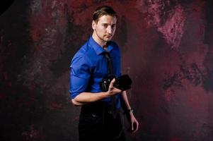 ritratto in studio di elegante fotografo professionista uomo con fotocamera, indossare su camicia blu e cravatta. foto