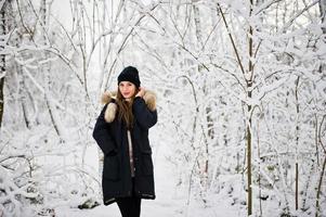 bella ragazza bruna in abiti caldi invernali. modello su giacca invernale e cappello nero. foto