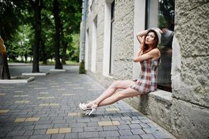 incredibili gambe lunghe con i tacchi alti indossano la ragazza sul cappello seduto sul davanzale della finestra per le strade della città. foto