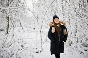 bella ragazza bruna in abiti caldi invernali. modello su giacca invernale e cappello nero. foto