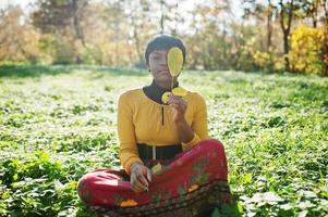 ragazza afroamericana in abito giallo e rosso al parco autunnale. foto