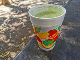 succo di frullato verde sulla panchina in un parco sullo sfondo di legno. foto