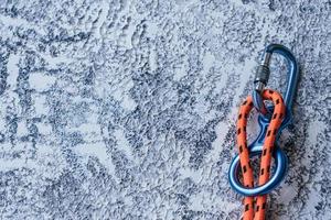 concezione dell'alpinismo. foto isolata di attrezzatura da arrampicata. parte del moschettone adagiata sulla superficie di colore bianco e grigio