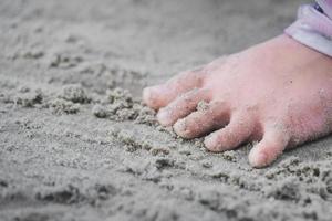 primo piano piccoli piedi di bambino in piedi sulla sabbia al bordo della spiaggia. durante la stagione estiva o primaverile. concetto di sviluppo sensoriale. spazio vuoto per inserire il testo. foto