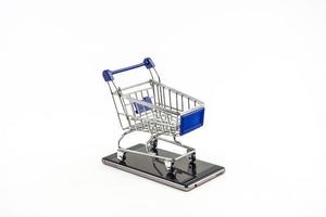 smart phone con carrello su sfondo bianco, significa shopping online foto