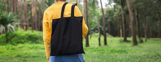 donna che tiene una borsa di cotone nero sullo sfondo della natura foto