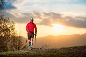 atleta uomo con sentiero di barba con bastoncini al tramonto foto