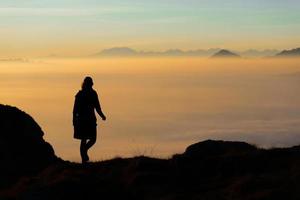 sagoma di un escursionista in montagna con il mare di nebbia in th foto