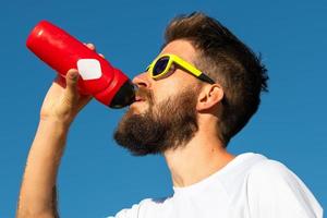 l'uomo sportivo beve dalla tua bottiglia d'acqua foto