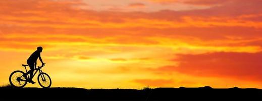 sagoma di un mountain biker godendo in discesa durante il tramonto. concetto di mountain bike. gara di mountain bike - ciclista silhouette sullo sfondo. foto