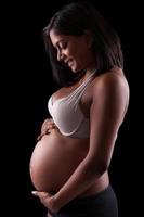 giovane bella donna indiana incinta che tocca la sua pancia foto