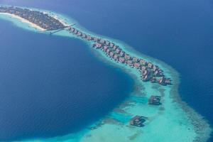 vista aerea panoramica del paesaggio marino su un atollo delle Maldive. spiaggia di sabbia bianca, barriera corallina vista dall'alto. foto