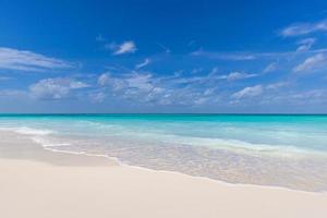 primo piano di sabbia sulla spiaggia e sul cielo estivo blu. paesaggio panoramico della spiaggia. spiaggia tropicale vuota e vista sul mare. cielo blu soleggiato, sabbia soffice, calma, luce solare tranquilla e rilassante, umore estivo foto