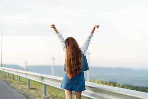 donna felice che si gode la vita nel campo con la foresta. bellezza della natura, cielo nuvoloso blu e campo colorato con la natura. stile di vita all'aperto. concetto di libertà. foto