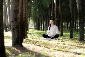 donna asiatica in buona salute attraente che medita nel parco foto