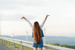 donna felice che si gode la vita nel campo con la foresta. bellezza della natura, cielo nuvoloso blu e campo colorato con la natura. stile di vita all'aperto. concetto di libertà. foto