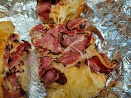 panino caldo con pastrami e crauti e formaggio su carta stagnola foto