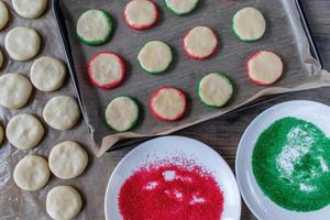 fare i biscotti di zucchero di Natale con spruzzata rossa e verde vista dall'alto foto