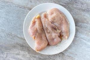 tre petti di pollo crudi con condimento piatto foto