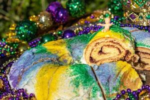 mardi gras king cake sormontato da una corona circondata da perline e decorazioni foto