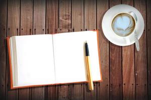 tavolo in legno con libro arancione con caffè caldo foto