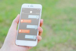 telefono della holding della mano della donna con il messaggero dell'app sullo schermo foto
