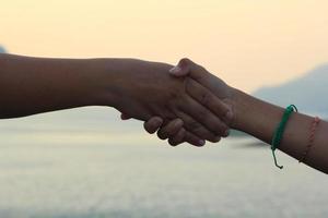 la stretta di mano rappresenta l'amicizia, il tocco amichevole - l'amore - il calore in famiglia e gli altri sullo sfondo, il cielo e le montagne la sera. foto