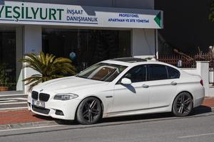 lato turchia marzo 01 2022 bianco bmw serie 5 è parcheggiato per strada in una calda giornata sullo sfondo di un edificio, negozio foto