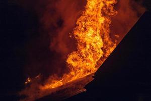 casa in fiamme di notte. temi di incendi dolosi, disastri ed eventi estremi. foto