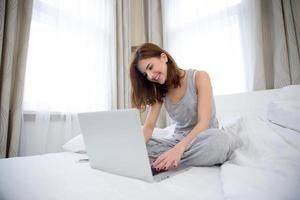 donna che per mezzo del computer portatile sul letto hte a casa
