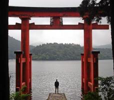 uomo in piedi vicino a torii a hakone, in giappone foto
