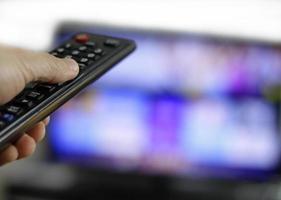 telecomando e schermo - abbuffarsi di guardare il programma televisivo preferito foto